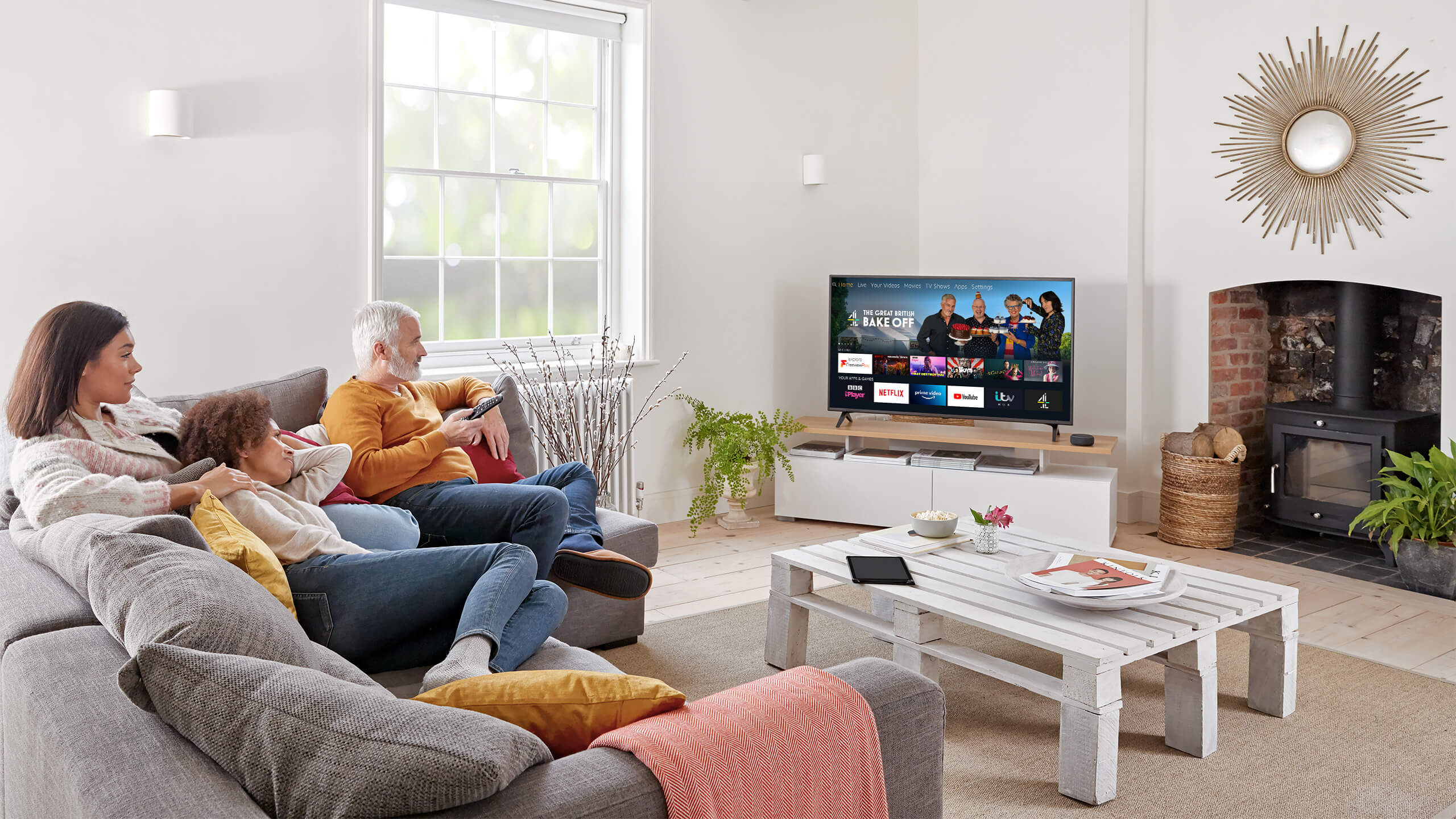 Three people seated on a sofa watching TV