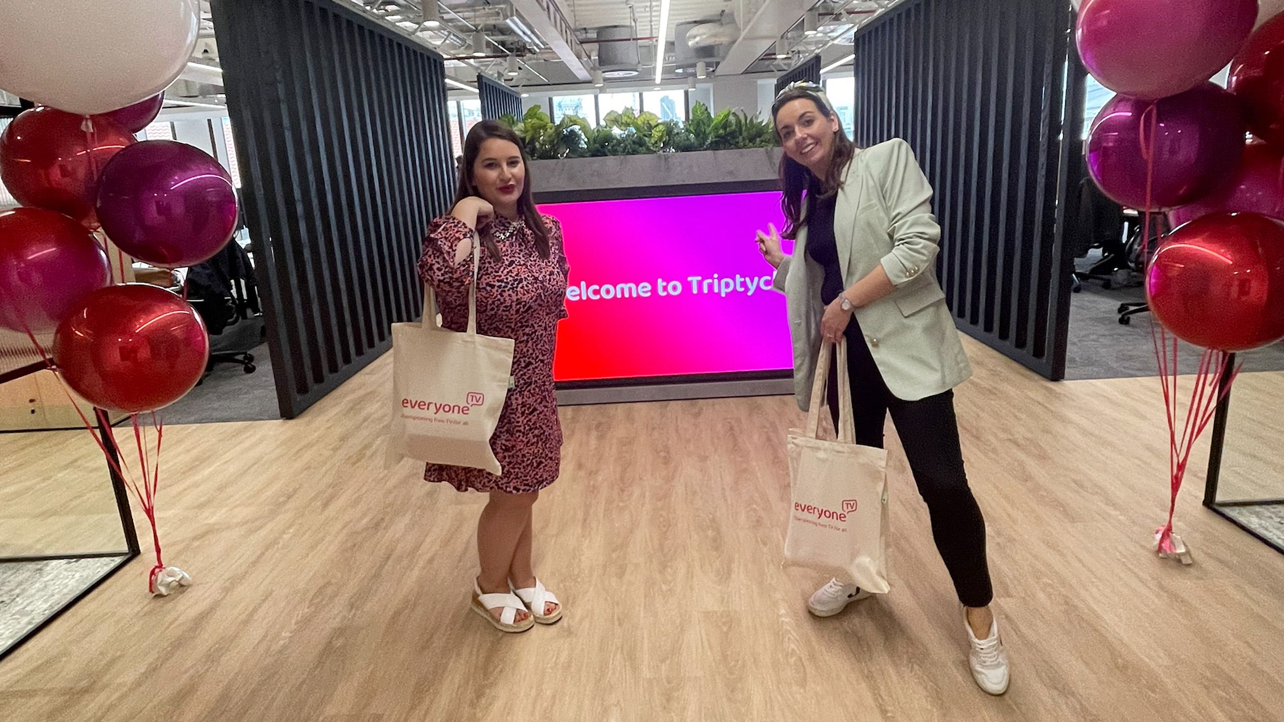Two woman standing in front of a screen displaying 'Welcome to Triptych'