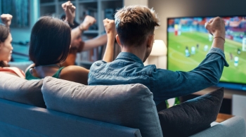 Group of people watching sport on TV and cheering