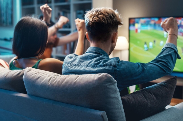 Group of people watching sport on TV and cheering