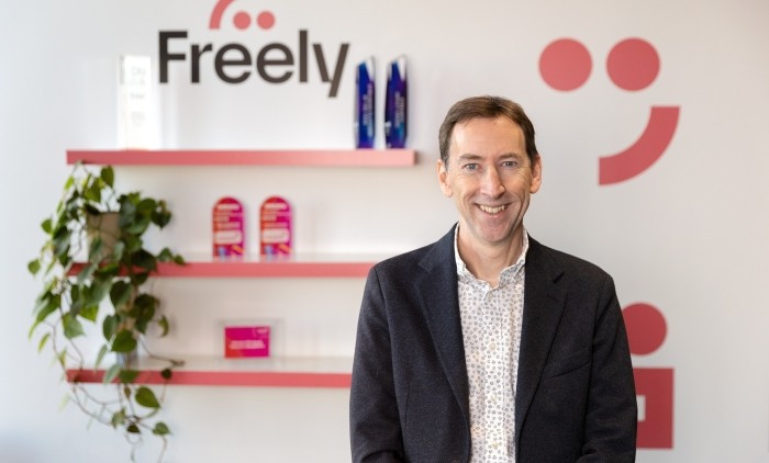 Jonathan Thompson of Freely stands in front of a Freely background